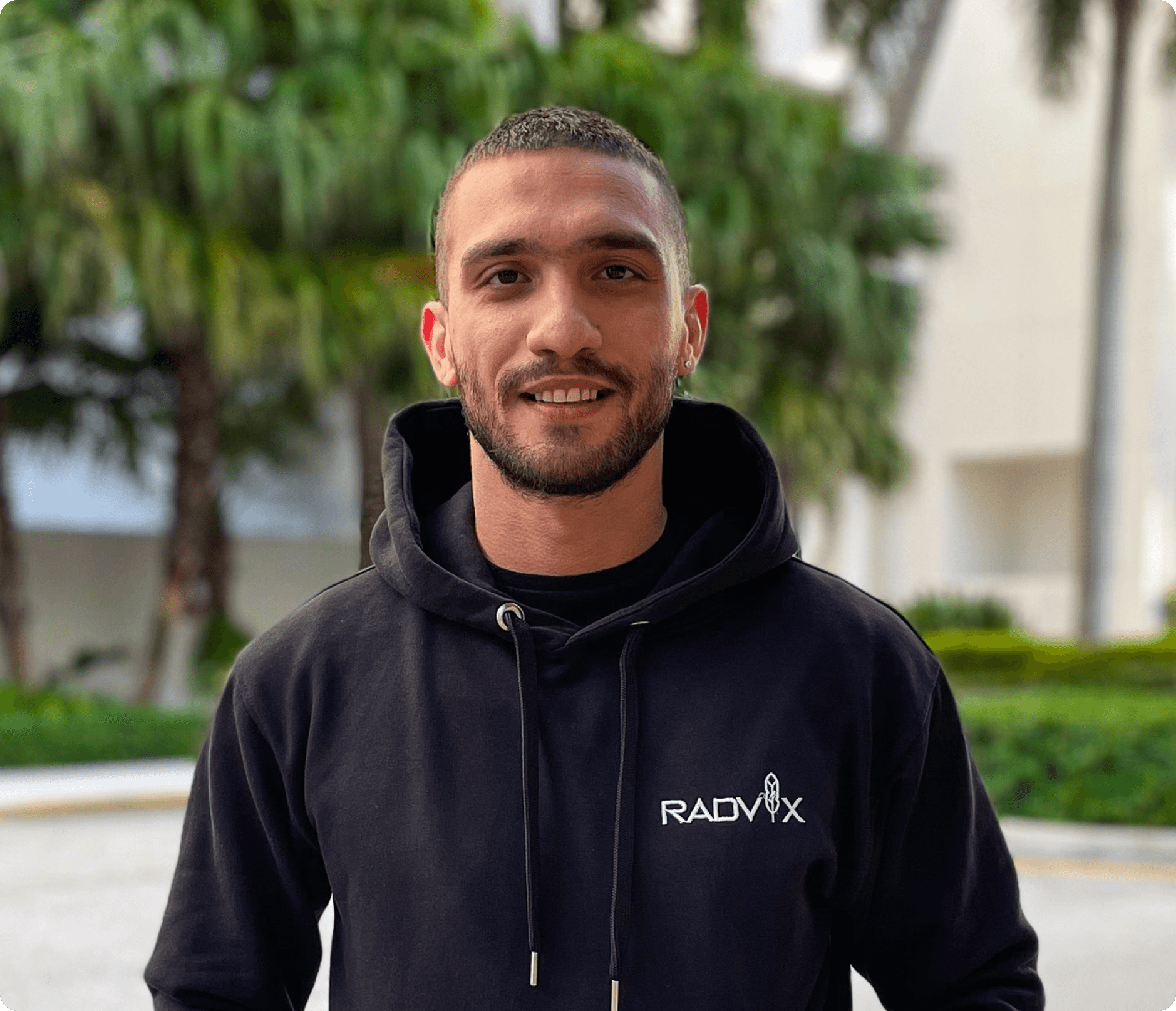 Photo of Nima Hosseinzadeh, Founder, standing outdoors and wearing a Radvix hoodie, smiling.